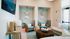 Elegant living area with modern decor featuring cozy wicker armchairs, stylish teal accents, and a chic wall design.