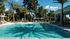 Luxurious outdoor pool area with sun loungers and tropical palm trees, perfect for relaxation in a serene setting.