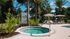 Inviting outdoor spa with lush greenery and comfortable lounge chairs, perfect for relaxation under the sun.