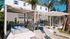 Luxurious outdoor seating area featuring stylish loungers, modern cabanas, and vibrant palm trees under a clear blue sky.