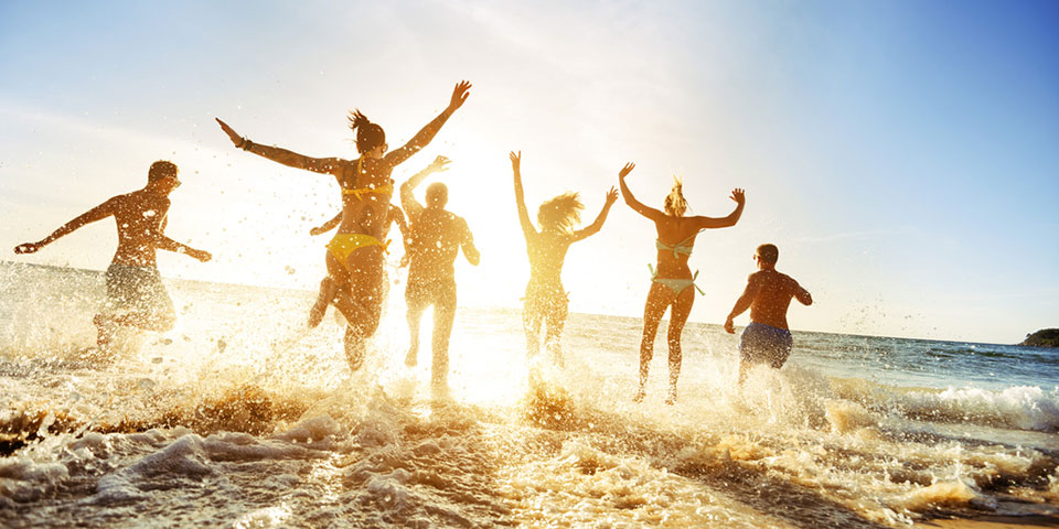 People in their bathing suits running on a beach and splashing in the waves in Lake Michigan.